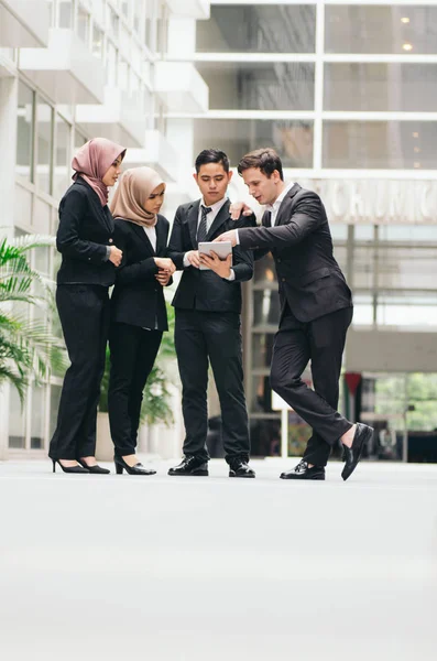 Group of young executive people in formalwear holding tablet and discussing something.