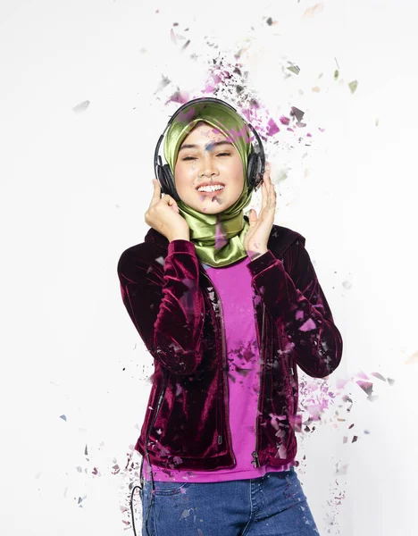 Studio shot, portrait of young beautiful Asian muslim wearing hijab listening to music with headset — Stockfoto
