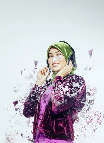 Stúdió lövés, portré a fiatal gyönyörű ázsiai muszlim visel hidzsáb zenét hallgatni headset — Stock Fotó