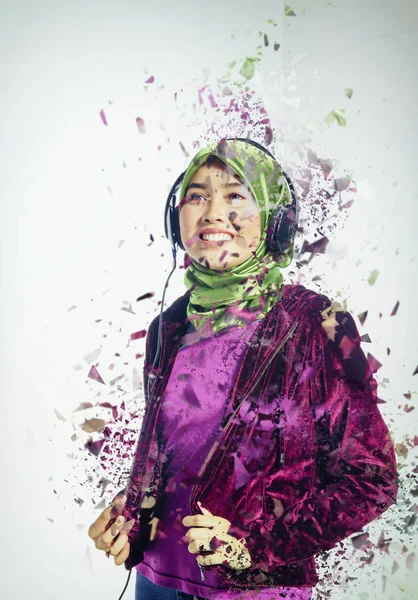 Studio shot, portrait of young beautiful Asian muslim wearing hijab listening to music with headset — Stockfoto