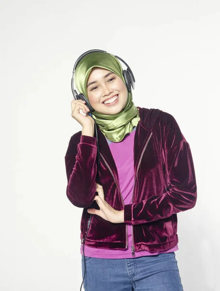 Studio shot, potret muda muslim Asia yang cantik mengenakan jilbab mendengarkan musik dengan headset — Stok Foto