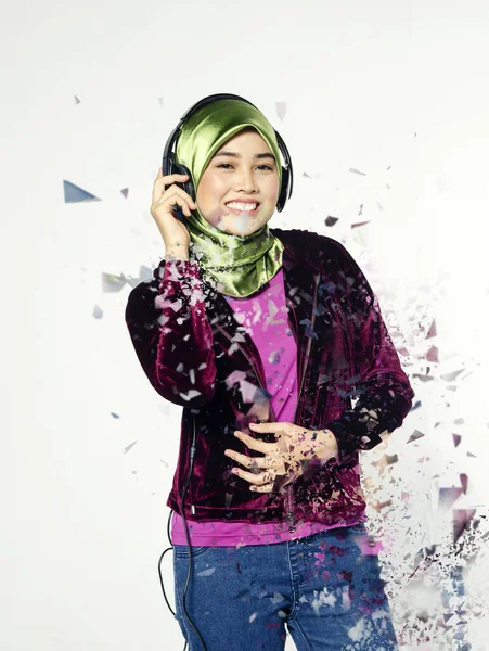 Studio shot, portrait of young beautiful Asian muslim wearing hijab listening to music with headset — Stock Photo, Image