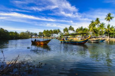 Güzel kırsal manzara, balıkçı teknesi ahşap iskelenin yanında demirlemiş mavi gökyüzü arkaplanı üzerinde