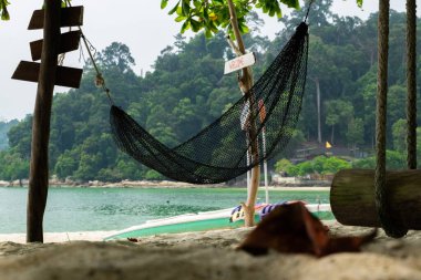 Perak State, Malezya 'daki Pangkor Adası' nda yaz tatili boyunca plajda dinlenmek için boş hamak