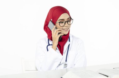Gülen surat tesettürlü genç doktor arkadaşlarını aramak için telefonunu kullandı.