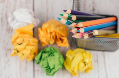 Okula ve ofislere geri dönüş, sabit konsept, renkli kalemler metal bir kutuda ve ahşap masa üzerinde buruşuk kağıt yığını.