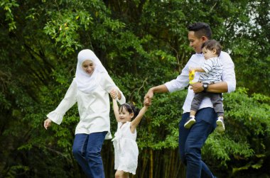 Mutlu aile kavramı, genç ebeveynlerin hafta sonları çocuklarıyla parkta vakit geçirmesi.