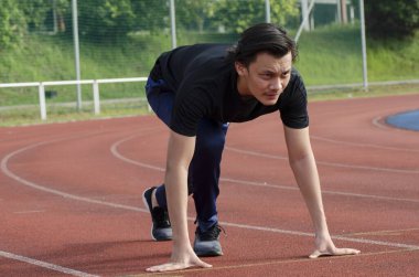 Genç erkek koşucu esneme egzersizi yapıyor, sabah antrenmanına hazırlanıyor.