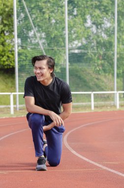 Genç erkek koşucu esneme egzersizi yapıyor, sabah antrenmanına hazırlanıyor.