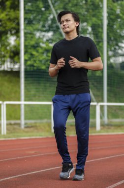 Genç erkek koşucu esneme egzersizi yapıyor, sabah antrenmanına hazırlanıyor.