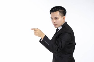 Kendine güvenen genç ve yakışıklı işadamı beyaz arka planda dikilirken başka tarafa bakıyor ve el kol hareketi yapıyor.