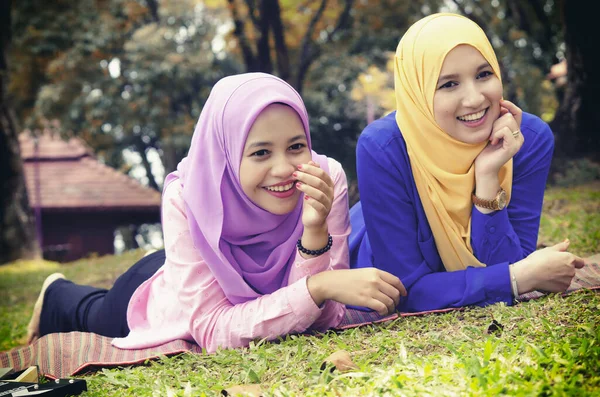 户外生活方式 友谊和幸福的概念 年轻的穆斯林躺在城市公园的草地上微笑的画像 — 图库照片