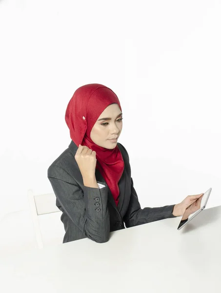 交流的概念 年轻女子头戴头巾 面带微笑地坐着 在白色背景下看她的平板电脑 — 图库照片