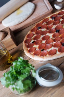 Salamlı pizza pepperonisi ve ahşap masa üzerindeki malzemeler rustik tarzında.