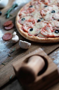 Sosisli ve malzemeli pizza ahşap masanın üzerinde, rustik tarzda.
