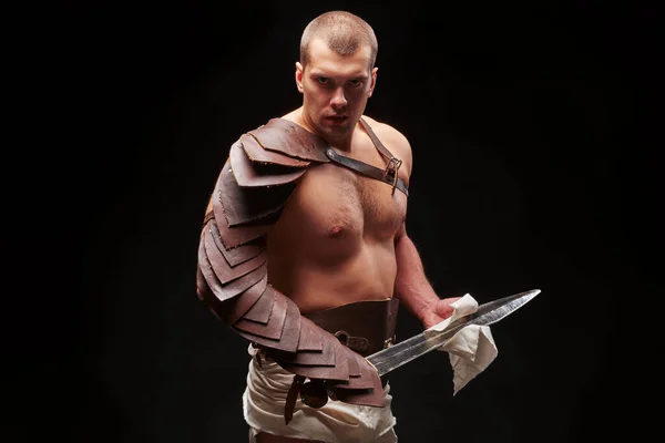 Gladiator with sword and armor on a black background — Stock Photo, Image