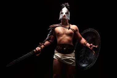Siyah arka planda kılıçlı ve zırhlı gladyatör