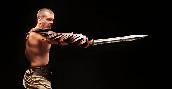 Gladiator with sword and armor on a black background — Stock Photo, Image