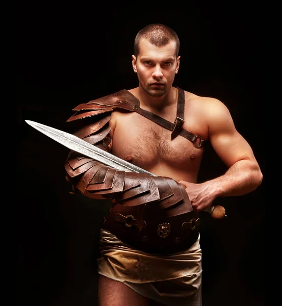 Gladiatore con spada e armatura su sfondo nero — Foto Stock