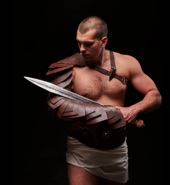 Gladiator with sword and armor on a black background — Stock Photo, Image