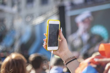 Bir kadın selfie çeker. Elinde akıllı telefon var..
