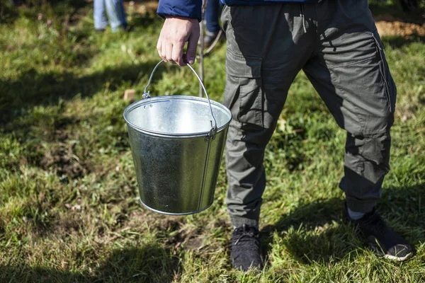 Gardener with a bucket. Metal bucket for water.