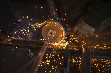 Bir adam öğütücüyle metal işliyor..