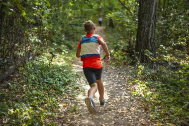 Koşu yarışması. Bir çocuk ormanda koşuyor..