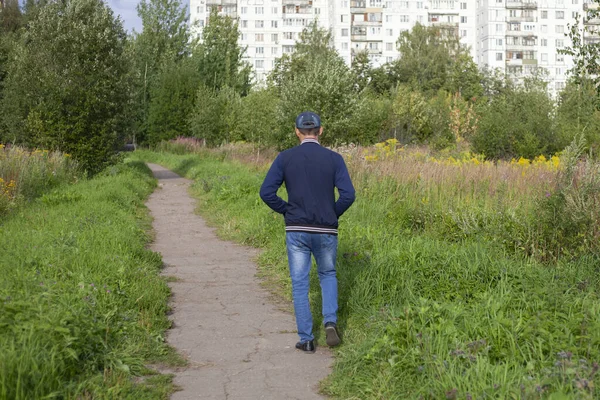 A man is walking along the street. Stranger in the park.