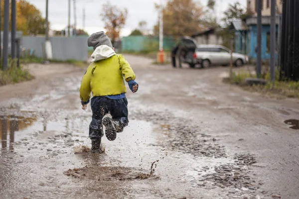 El chico corre entre los charcos. Niño desobediente — Foto de Stock