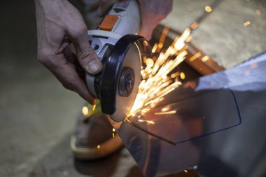 Metal kesimi. Öğütücü çelik. Öğütücü olarak çalış. Sürtünmeden kıvılcımlar çıkıyor. Erkek işi. Bir tasarım yaratıyorum. Atölyedeki proje. Demir işleme. El elektrikli aracı.