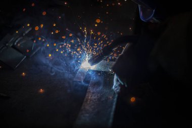 Metal kaynaklama. Elektrikli ısıtmadan kıvılcımlar. Atölyede çalış. Malzemelerin güvenilir şekilde birleştirilmesi. Demirin üretimi. Metal ustasının işi..