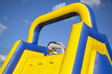 Eğlence için şişirilebilir engel. İnsanlar tepeye tırmanıyor. Atlamak için çocuk alanı. Şişme şehir. Açık havada trambolin merkezi. Erkekler duvara tırmanıyor..