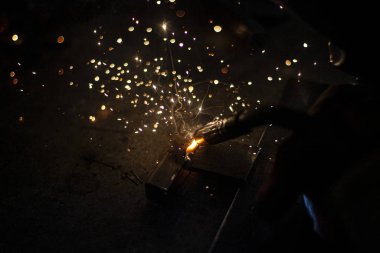 Metal kaynaklama. Elektrikli ısıtmadan kıvılcımlar. Atölyede çalış. Malzemelerin güvenilir şekilde birleştirilmesi. Demirin üretimi. Metal ustasının işi..