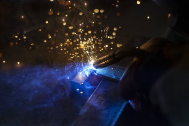 Metal kaynaklama. Elektrikli ısıtmadan kıvılcımlar. Atölyede çalış. Malzemelerin güvenilir şekilde birleştirilmesi. Demirin üretimi. Metal ustasının işi..