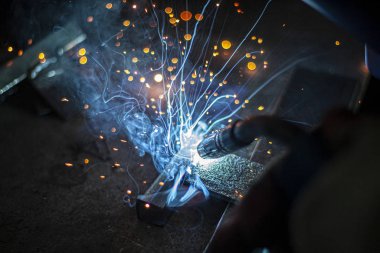 Metal kaynaklama. Elektrikli ısıtmadan kıvılcımlar. Atölyede çalış. Malzemelerin güvenilir şekilde birleştirilmesi. Demirin üretimi. Metal ustasının işi..