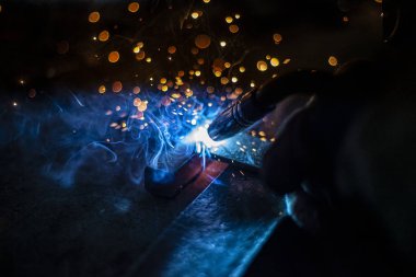 Metal kaynaklama. Elektrikli ısıtmadan kıvılcımlar. Atölyede çalış. Malzemelerin güvenilir şekilde birleştirilmesi. Demirin üretimi. Metal ustasının işi..