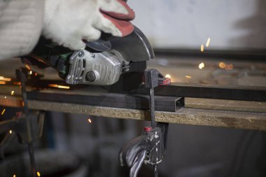 Metal kesimi. Öğütücü çelik. Öğütücü olarak çalış. Sürtünmeden kıvılcımlar çıkıyor. Erkek işi. Bir tasarım yaratıyorum. Atölyedeki proje. Demir işleme. El elektrikli aracı.