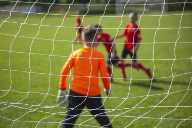 Kaleci topu yakalıyor. Hedefe odaklan. Spor müsabakası. Çocuk futbolu sahada. Fiziksel gelişim. Çocuk sporu. El çabukluğu. Top Şampiyonası.