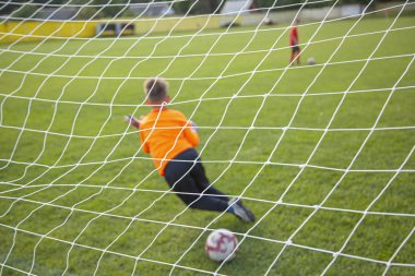 Kaleci topu yakalıyor. Hedefe odaklan. Spor müsabakası. Çocuk futbolu sahada. Fiziksel gelişim. Çocuk sporu. El çabukluğu. Top Şampiyonası.