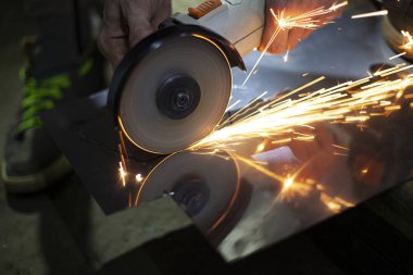 Metal kesimi. Öğütücü çelik. Öğütücü olarak çalış. Sürtünmeden kıvılcımlar çıkıyor. Erkek işi. Bir tasarım yaratıyorum. Atölyedeki proje. Demir işleme. El elektrikli aracı.