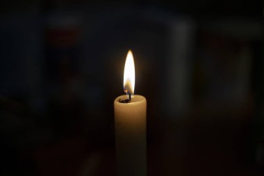 Tamamen karanlıkta mum alevi. Bir mum alevler içinde parlar. Fitil yanıyor. Dua için kilise mumu. Ortodoks ayini.