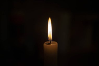 Tamamen karanlıkta mum alevi. Bir mum alevler içinde parlar. Fitil yanıyor. Dua için kilise mumu. Ortodoks ayini.