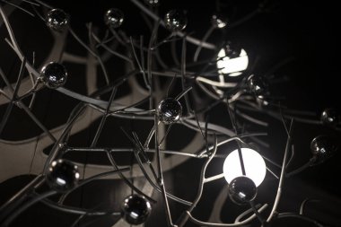 Güzel lambalar. Tasarımcı ışıkları. Dekor olarak metal toplar. Güzel bir iç mekan. Kıvrımlı çelik raflarda parlak lambaları olan koyu arkaplan..