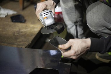 Metal kesimi. Öğütücü çelik. Öğütücü olarak çalış. Sürtünmeden kıvılcımlar çıkıyor. Erkek işi. Bir tasarım yaratıyorum. Atölyedeki proje. Demir işleme. El elektrikli aracı.