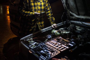 Yollara düş. Araba tamiri. Motor kaputta. Bir adam arabasında bir arıza arıyor. Kişisel araçların yapımının ayrıntıları. Mekanizmanın içindeki hasarın teşhisi.