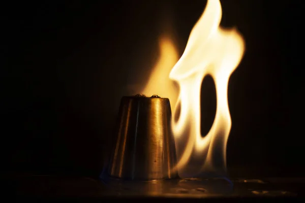 アルコールはアルコール飲料のためにスタック上で燃焼します 金属製のカップの周りに炎の舌 火の質感 黒い背景に黄色の火 バーで火事だ 酒に火をつける伝統 — ストック写真