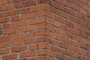 Brick wall texture. View of the brickwork from the corner of the building. Red background. Cement bonded building material. Part of the design.