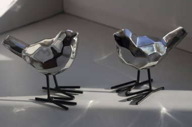 Figures of birds made of metal. Shiny tits in the form of sculptures. Decoration for the interior. Steel birds made in the polygonal style. Figurines in natural light.