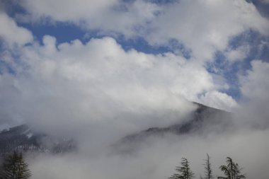 Baharın başlarında dağ manzarası. Sis dağlardan kayıyor. Kar zirveleri. Kayak merkezi. Çok güzel bir arka plan. Dağ sırasının geniş görüşü. Kuzey doğasının sakinliği.